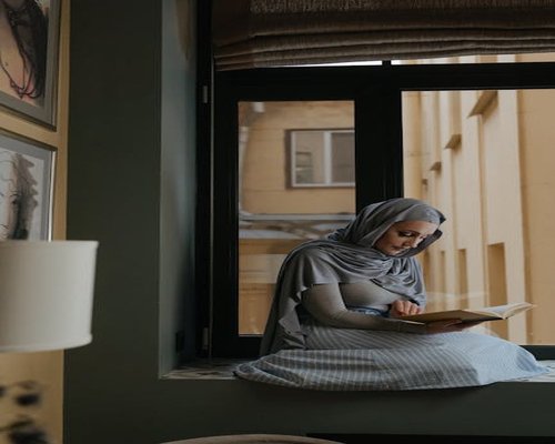 A person reading a book by the window