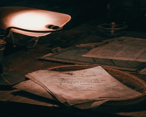 A desk lamp casting warm light on papers